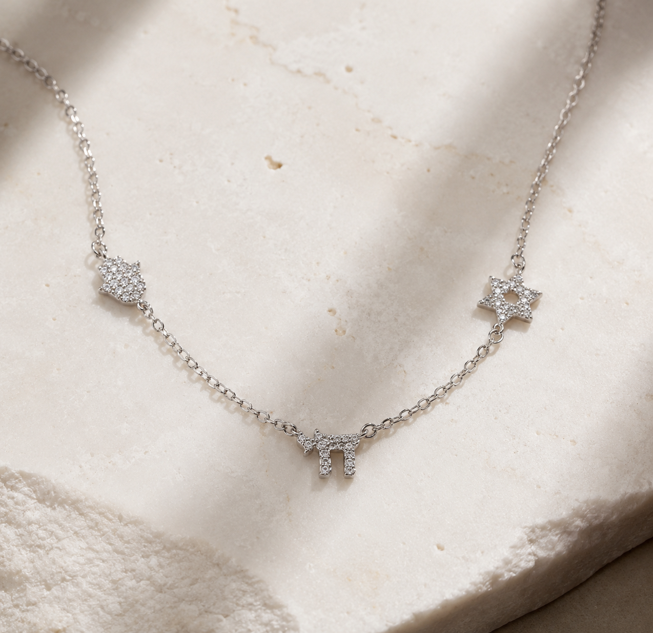 Silver tone 3 Pavé Charm Choker Necklace styled on a neutral stone surface.