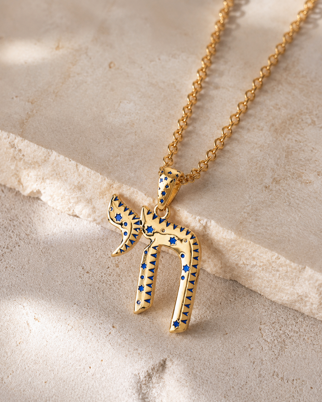 Gold tone TLV Chai Necklace styled on a natural stone surface.