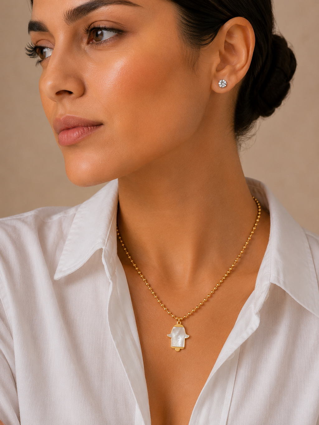 Model wearing the MOP Hamsa Necklace with a Hamsa pendant on a gold tone ball chain.