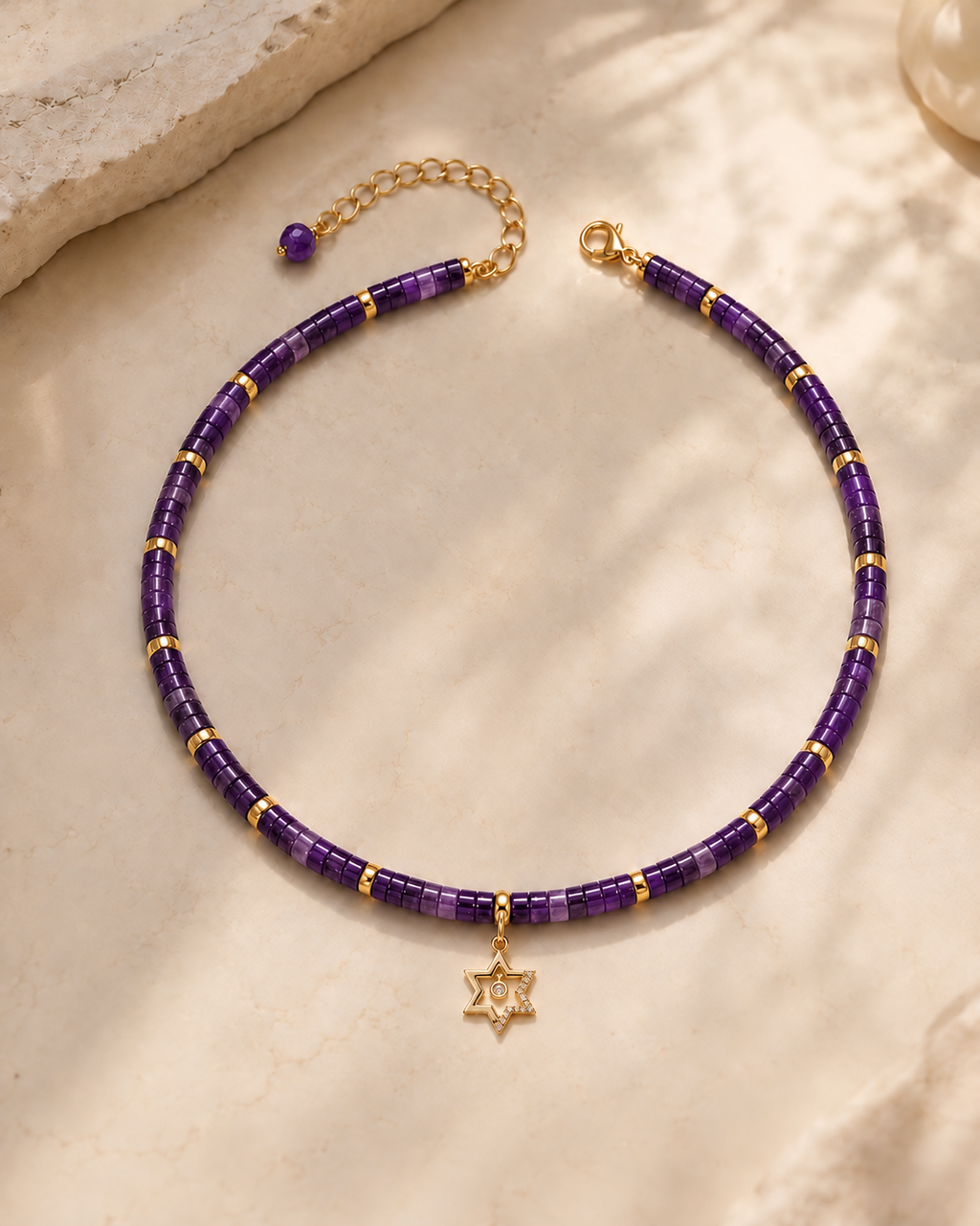 Noa Star of David Beaded Choker Necklace in Amethyst with gold tone details on neutral stone surface.