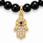 Close-up of Adele Black Beaded Necklace with gold tone Hamsa charm and evil eye motif.