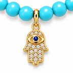Close-up of gold tone Hamsa charm and turquoise beads.