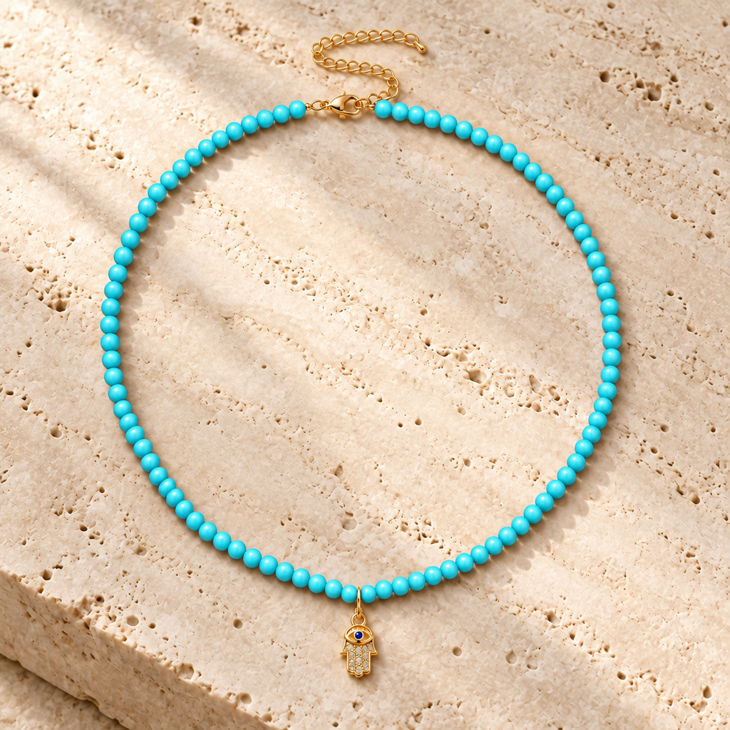 Adele Hamsa Beaded Necklace in Turquoise on textured stone.