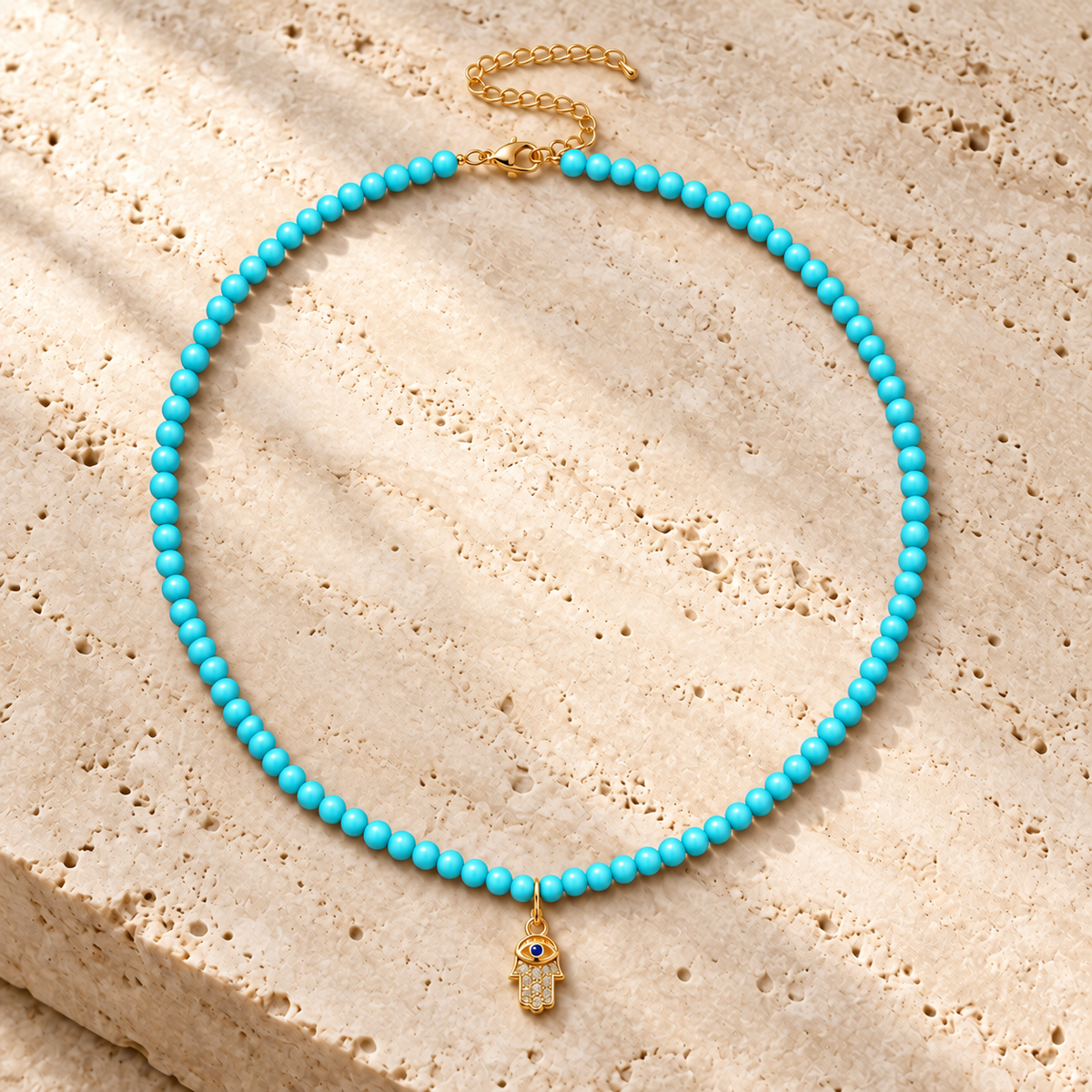 Adele Hamsa Beaded Necklace in Turquoise on textured stone.