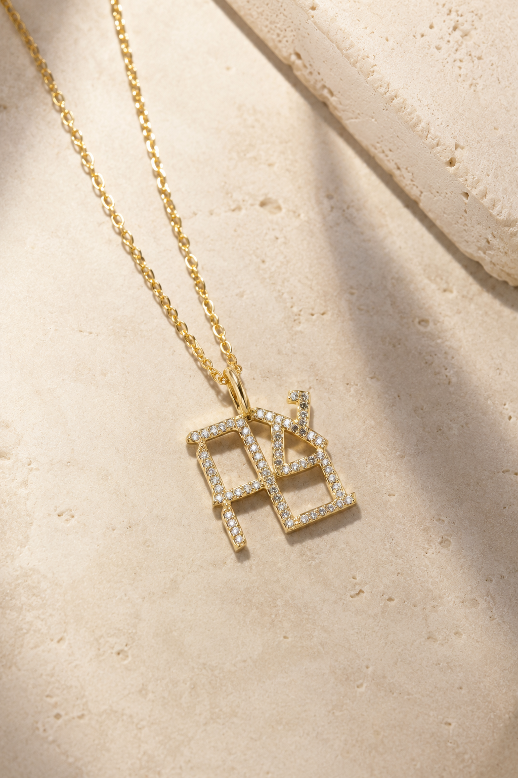 Gold tone Ahava Love Necklace styled on a neutral stone surface.