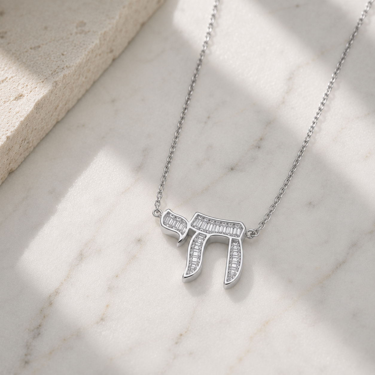 Silver tone Baguette Chai Necklace styled on a neutral stone surface.