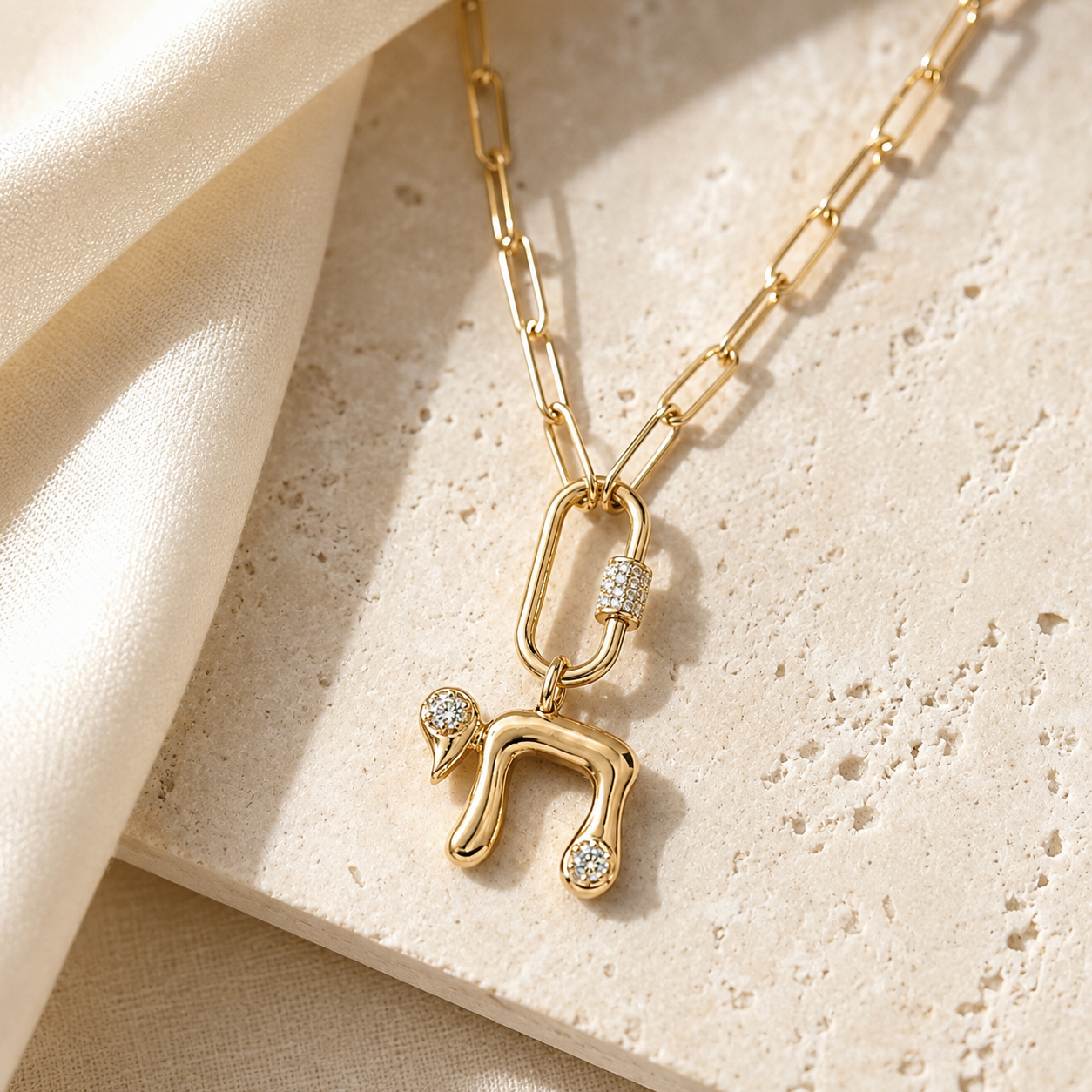 Gold tone Bubble Chai Lariat Necklace styled on a neutral stone surface.