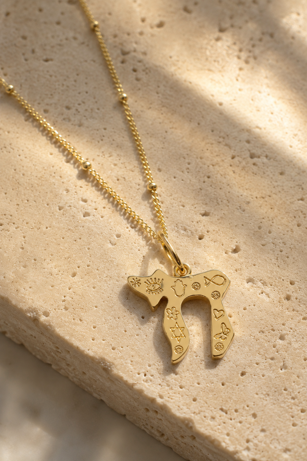 Gold tone Carved Chai Necklace styled on a natural stone surface.