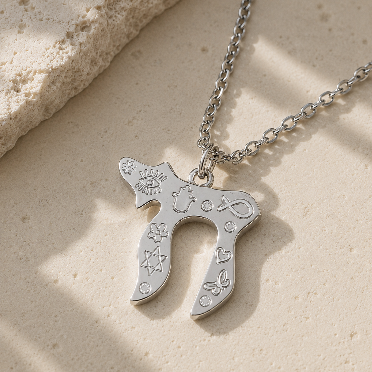 Silver tone Carved Chai Necklace styled on a natural stone surface.