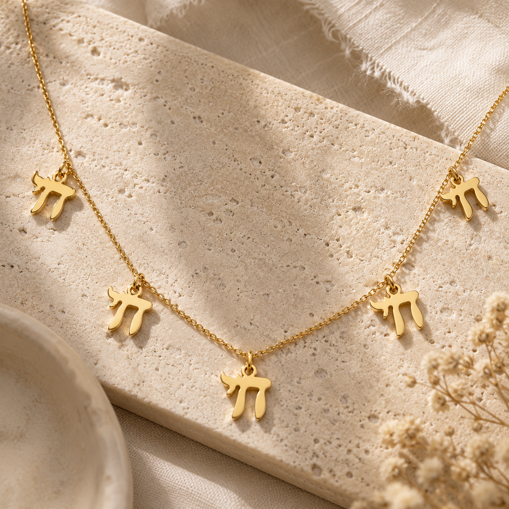 Gold tone “Chai on Life” Choker Necklace styled on a neutral stone surface.