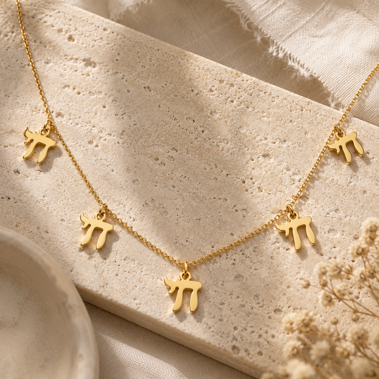 Gold tone “Chai on Life” Choker Necklace styled on a neutral stone surface.