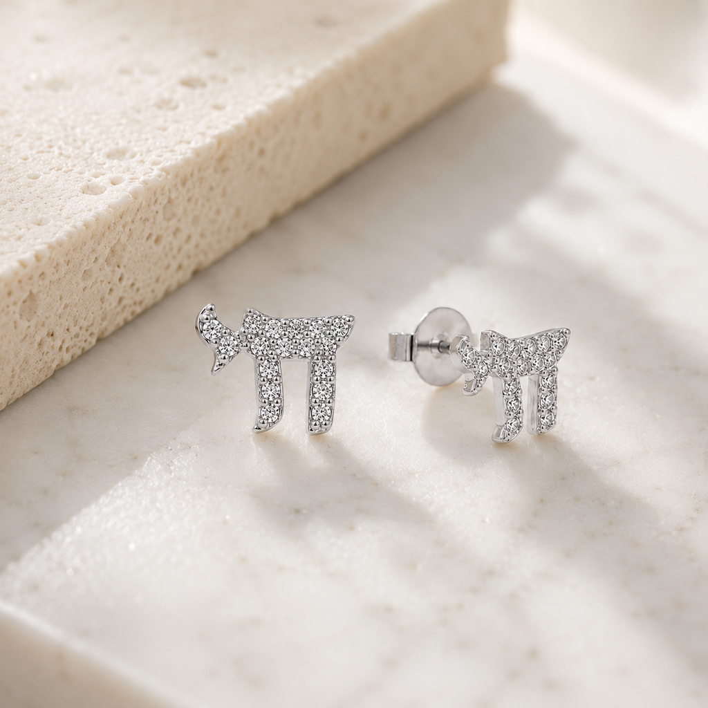 Silver tone Chai Pavé Stud Earrings styled on a neutral stone surface.