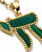 Close-up of the gold tone Chai pendant with green bead-like detailing.