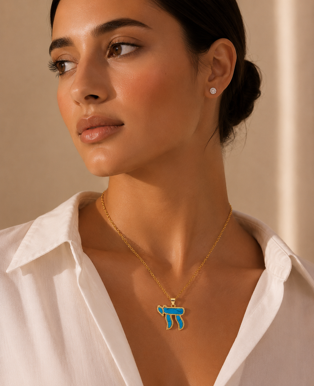 Model wearing the gold tone Perlée Chai Necklace with a turquoise Chai pendant.