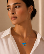 Model wearing the gold tone Perlée Chai Necklace with a turquoise Chai pendant.