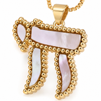 Close-up of the Perlée Chai pendant with white pearl-effect detailing and a gold tone finish.