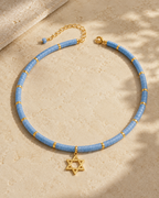 Blue quartz Dead Sea Magen David necklace styled on a neutral stone surface.