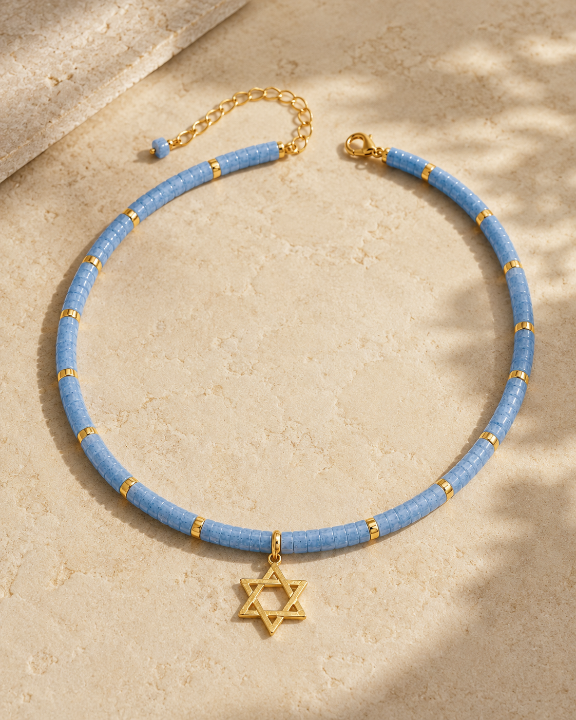 Blue quartz Dead Sea Magen David necklace styled on a neutral stone surface.
