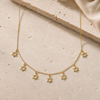 Gold Tone Divine Protection Necklace with seven Star of David charms displayed on a luxury neutral stone surface.