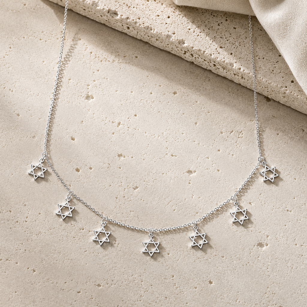 Silver Tone Divine Protection Necklace with seven Star of David charms displayed on a luxury neutral stone surface.