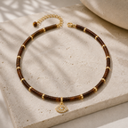Eden Evil Eye Beaded Choker Necklace with Tiger's Eye gemstone beads styled on a neutral stone surface.