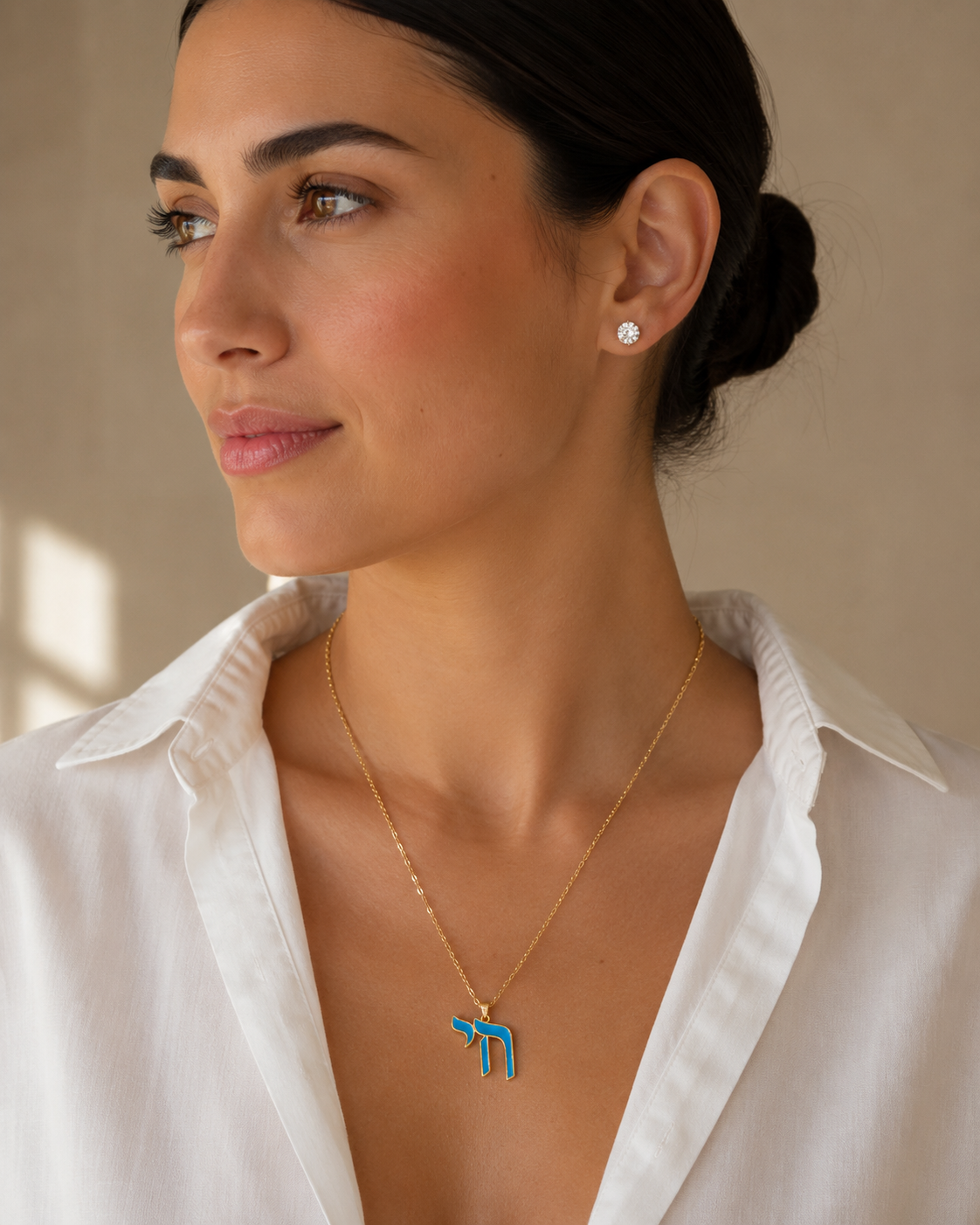 Model wearing the gold tone Enamel Chai Necklace with blue enamel detailing.