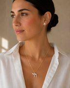 Model wearing the gold tone Enamel Chai Necklace with white enamel detailing.