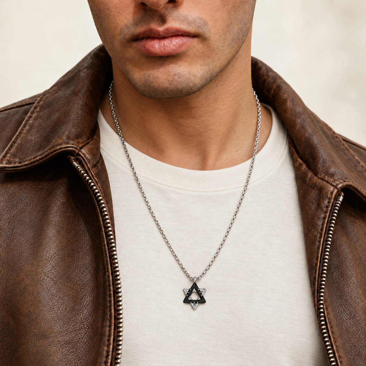 Man wearing the Ezra black Star of David necklace over an ivory T-shirt with a brown leather jacket.