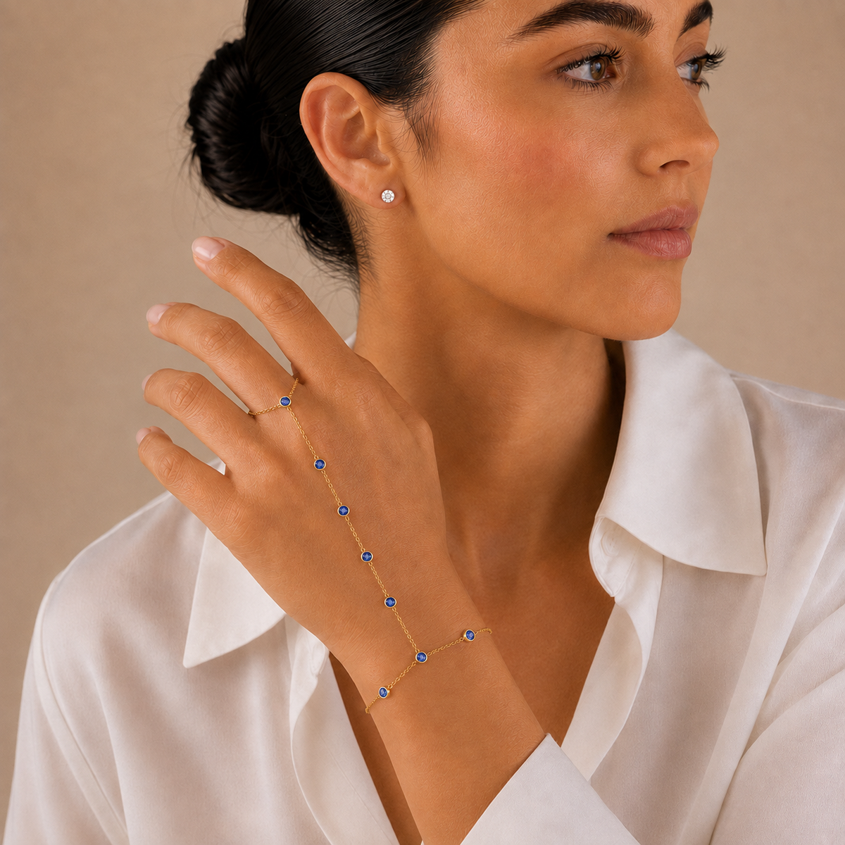 Woman wearing the gold tone Hava CZ Hand Chain with sapphire-colored cubic zirconia.