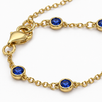 Close-up of the gold tone Hava CZ Hand Chain with bezel-set sapphire-colored cubic zirconia.