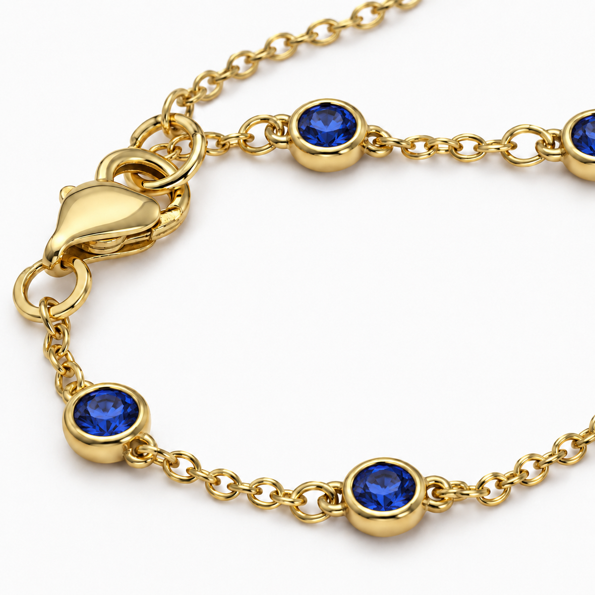 Close-up of the gold tone Hava CZ Hand Chain with bezel-set sapphire-colored cubic zirconia.