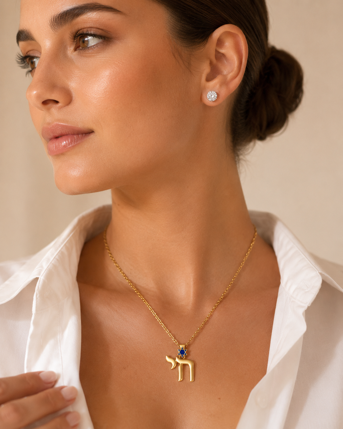Model wearing the gold tone Jerusalem Chai Necklace with navy enamel Star of David detailing.