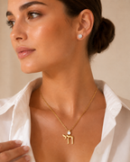 Model wearing the gold tone Jerusalem Chai Necklace with white enamel Star of David detail.