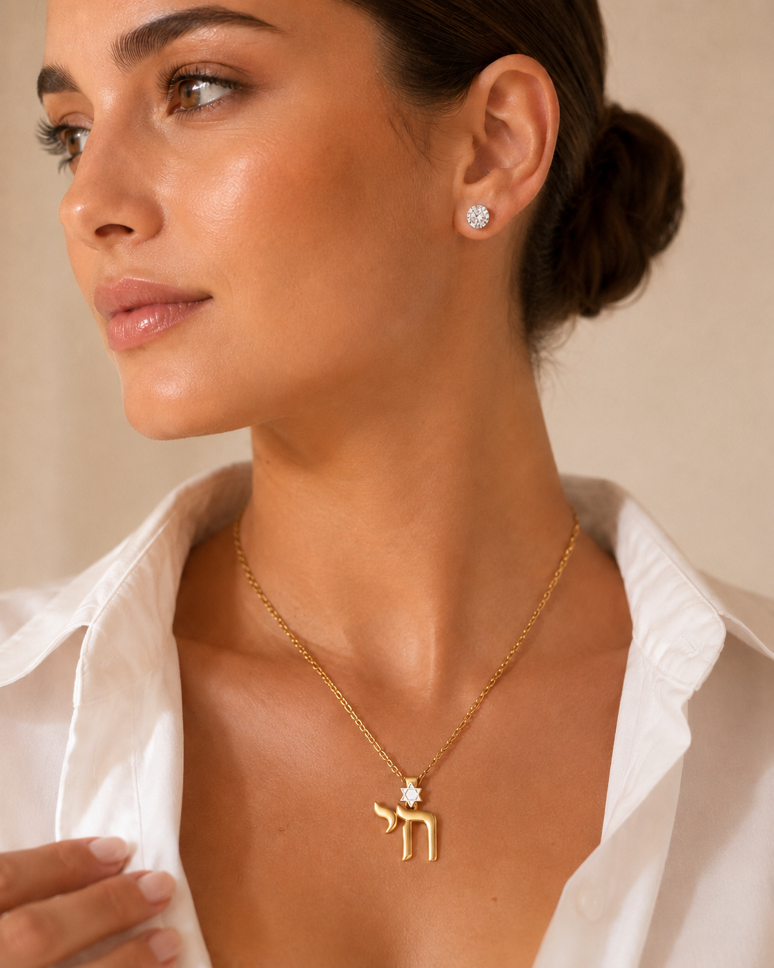 Model wearing the gold tone Jerusalem Chai Necklace with white enamel Star of David detail.