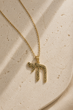Gold tone Laser-Cut Chai Necklace styled on a textured neutral surface.