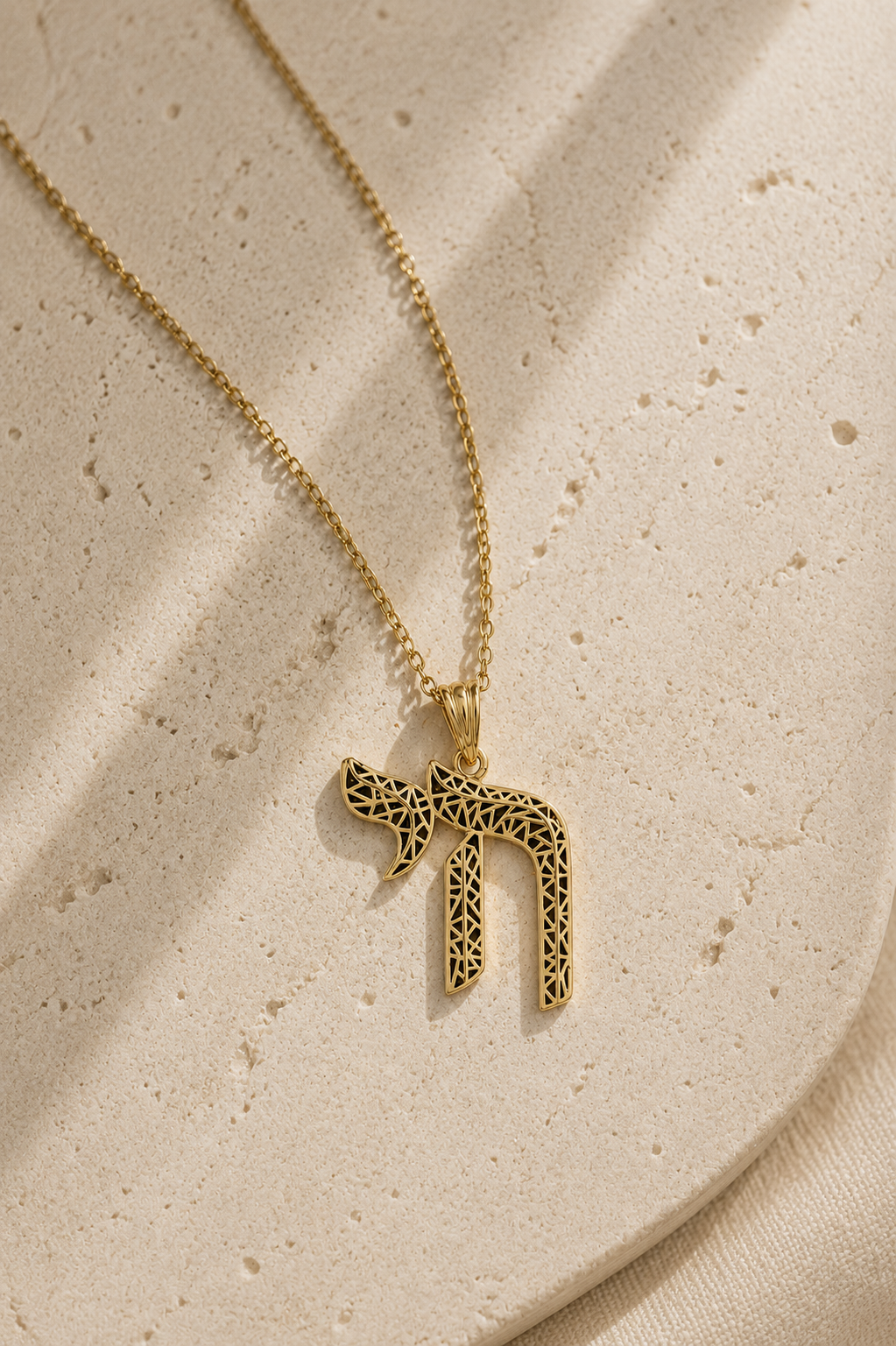 Gold tone Laser-Cut Chai Necklace styled on a textured neutral surface.
