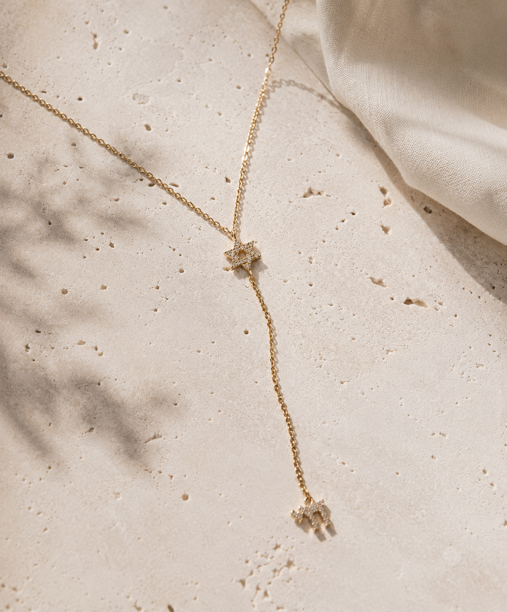 Gold tone Magen David Lariat Necklace styled on a neutral stone surface.
