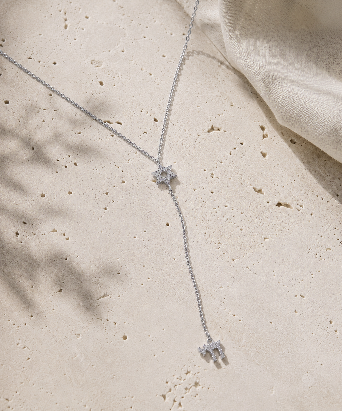 Silver tone Magen David Lariat Necklace styled on a neutral stone surface.