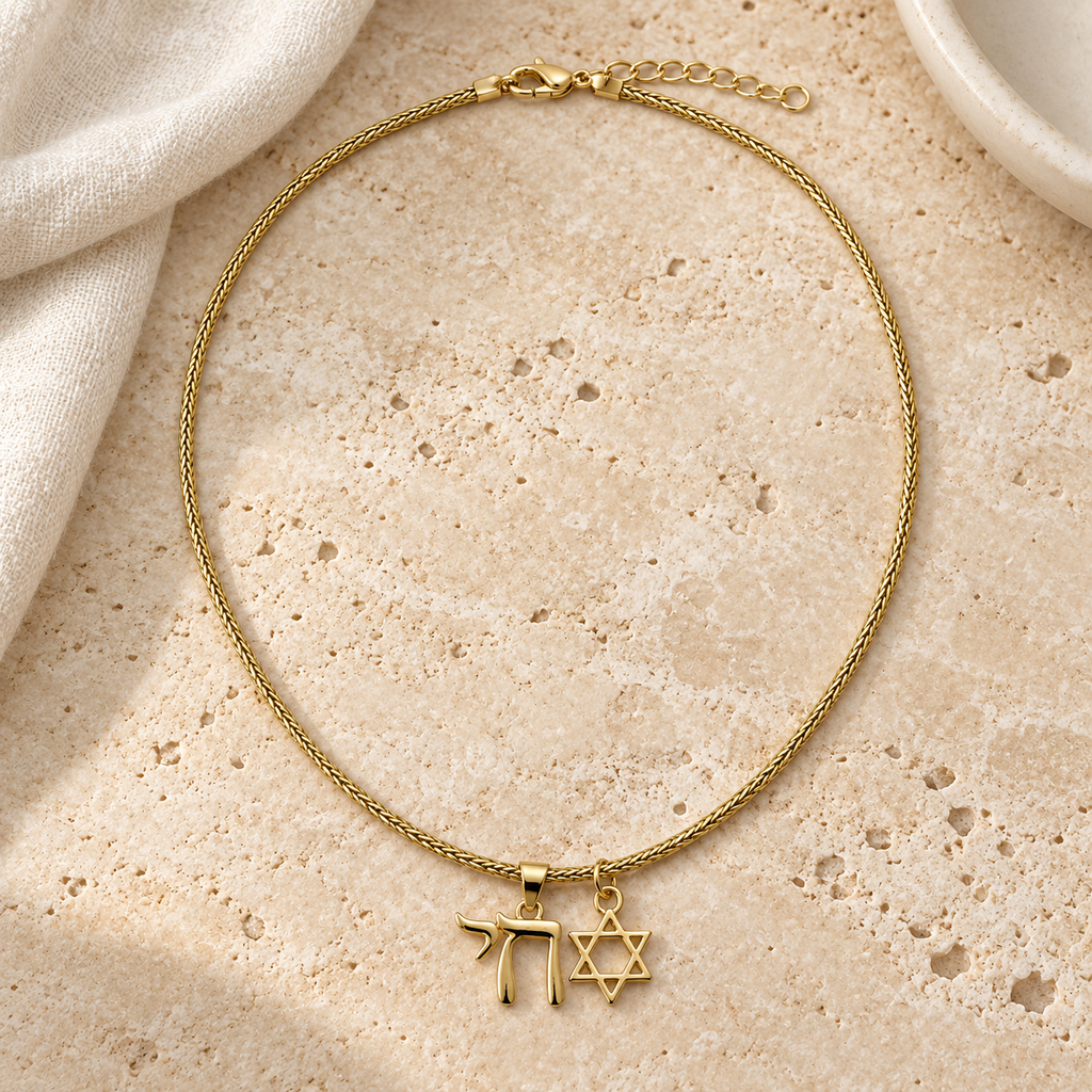 Neshama Charm Necklace arranged on pale travertine beside ivory linen and an ivory ceramic dish.