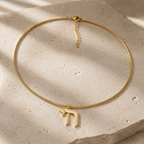 Gold tone Outline Pavé Chai choker styled on a neutral stone surface.