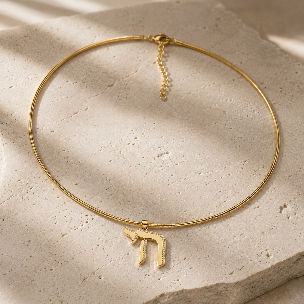 Outline Pavé Chai Collar Necklace in Gold Tone on neutral stone surface.