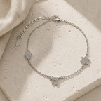 Silver Tone Pavé Trio Bracelet with Star of David, Hamsa, and Chai charms on a luxury neutral stone surface.