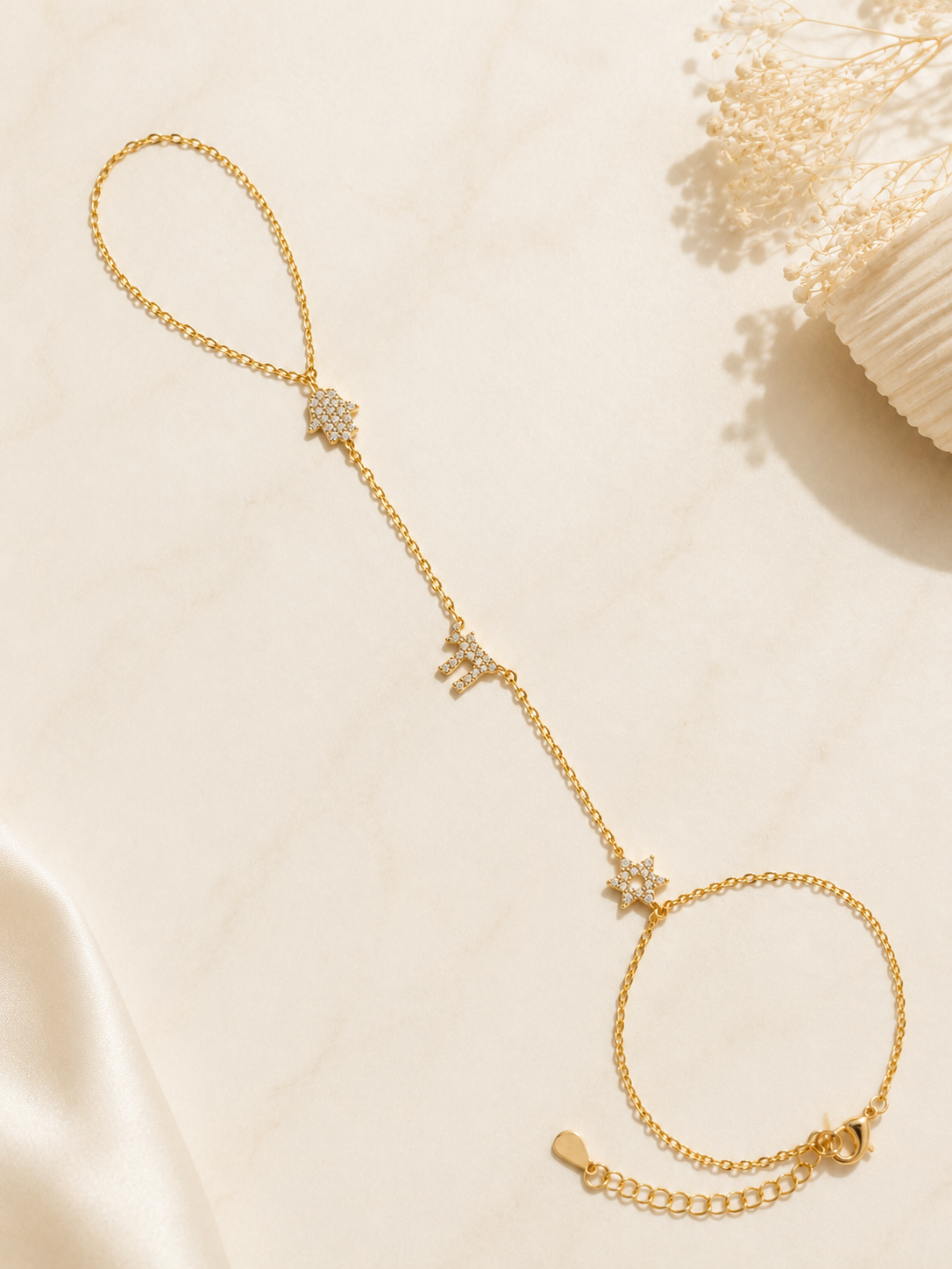 Gold tone Pavé Trio Hand Chain styled on a neutral stone surface.