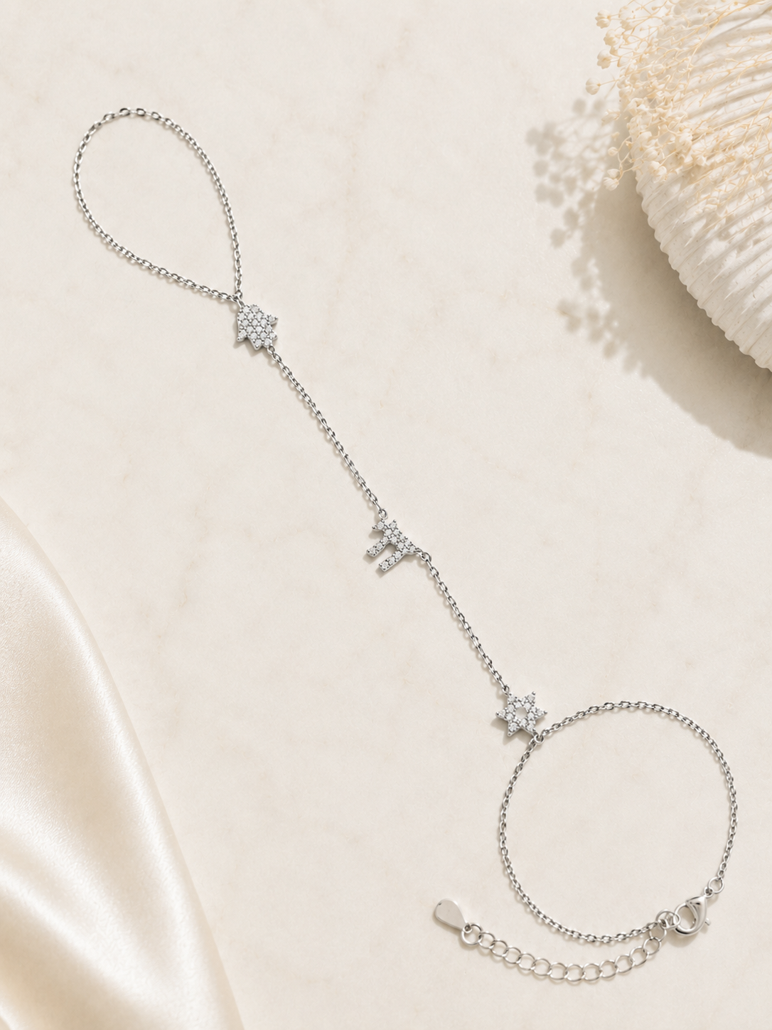 Silver tone Pavé Trio Hand Chain styled on a neutral stone surface.