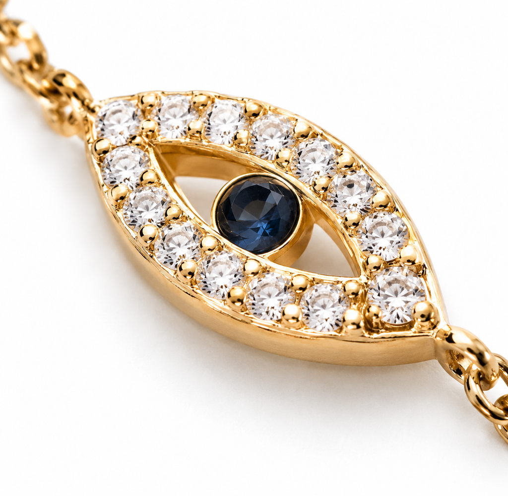 Close-up of the gold tone evil eye charm with a blue center and sparkling stone accents.
