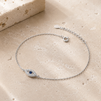 Silver tone Petite Evil Eye Bracelet styled on a neutral stone surface.