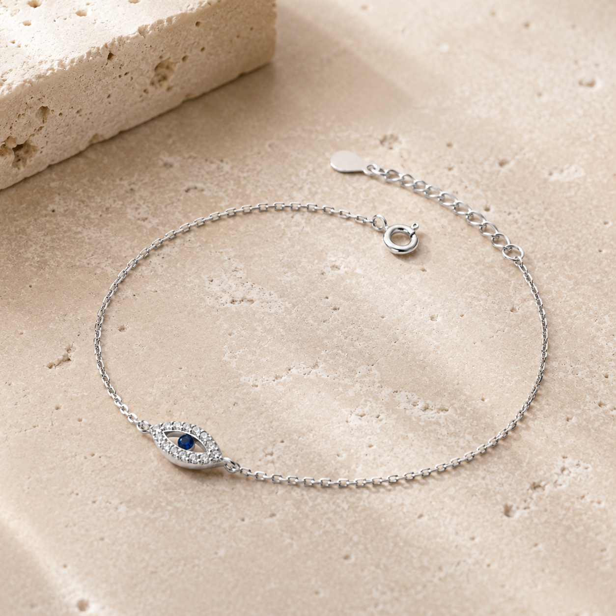 Silver tone Petite Evil Eye Bracelet styled on a neutral stone surface.
