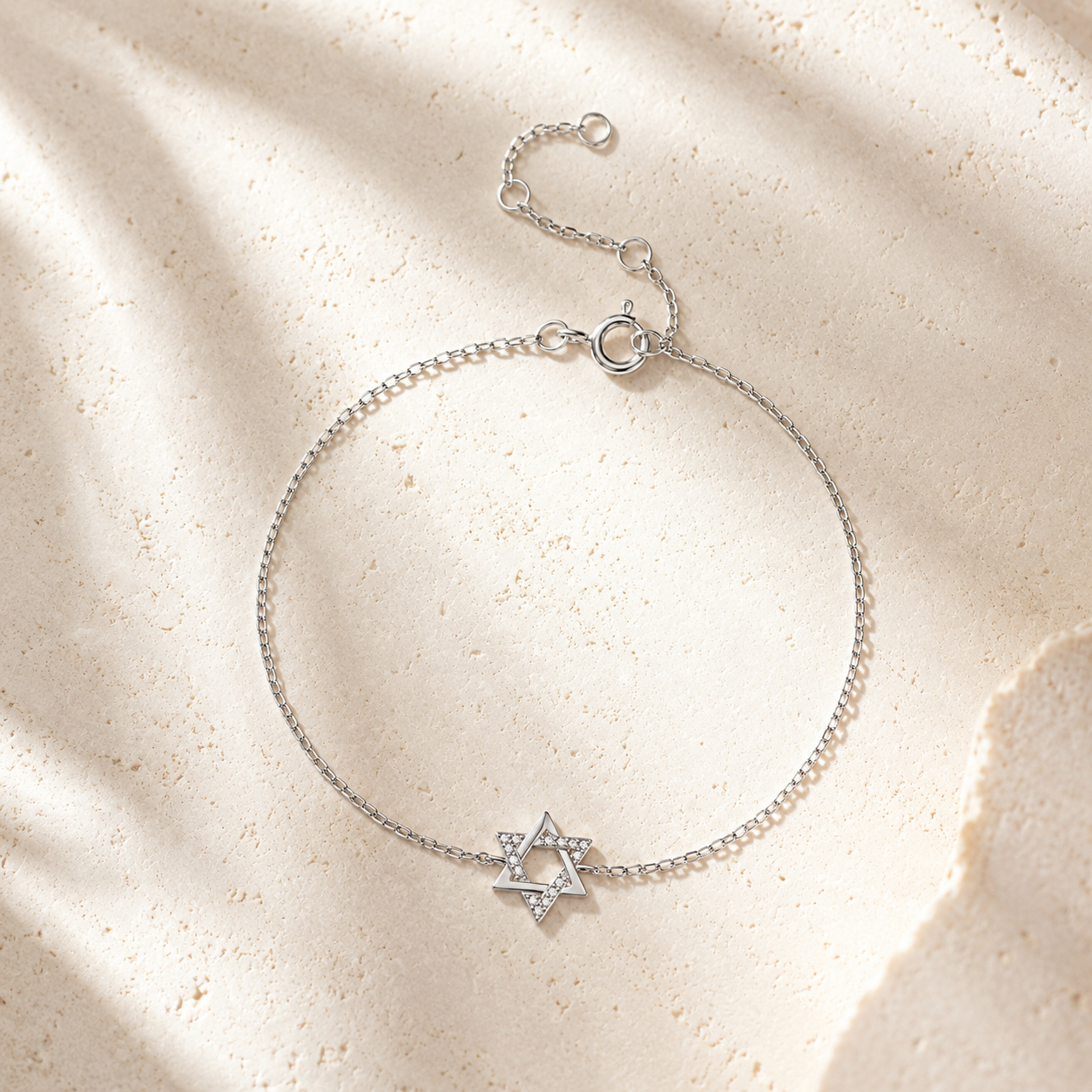 Silver tone Petite Magen David Bracelet styled on a neutral stone surface.