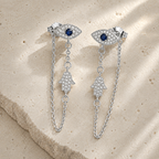 Silver Tone Protection Drop Chain Earrings displayed on a luxury neutral stone surface.