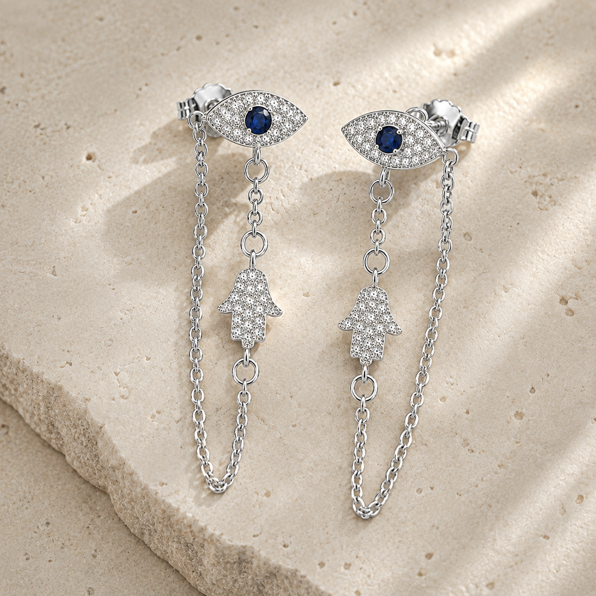 Silver Tone Protection Drop Chain Earrings displayed on a luxury neutral stone surface.